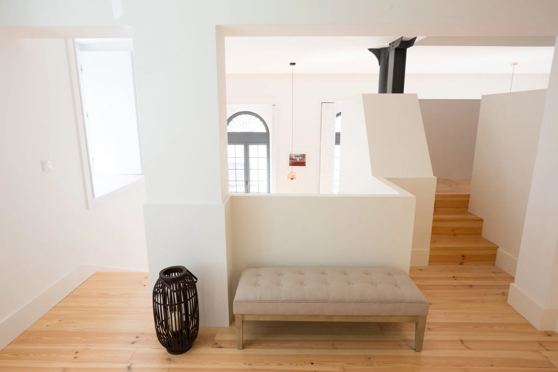 Un interior luminoso con suelo de madera, un banco y una escalera.