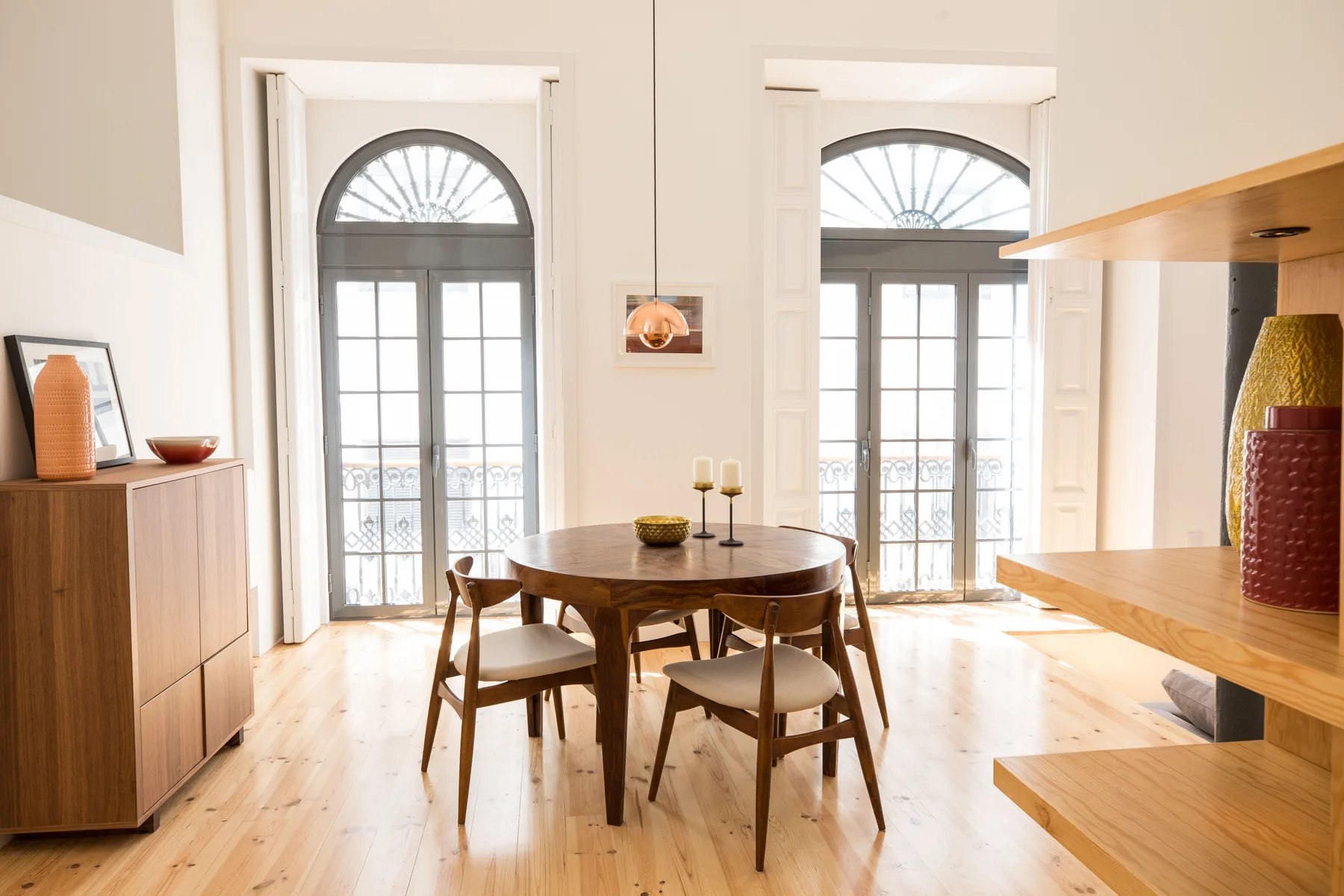 Comedor luminoso con una mesa redonda y altas ventanas arqueadas.
