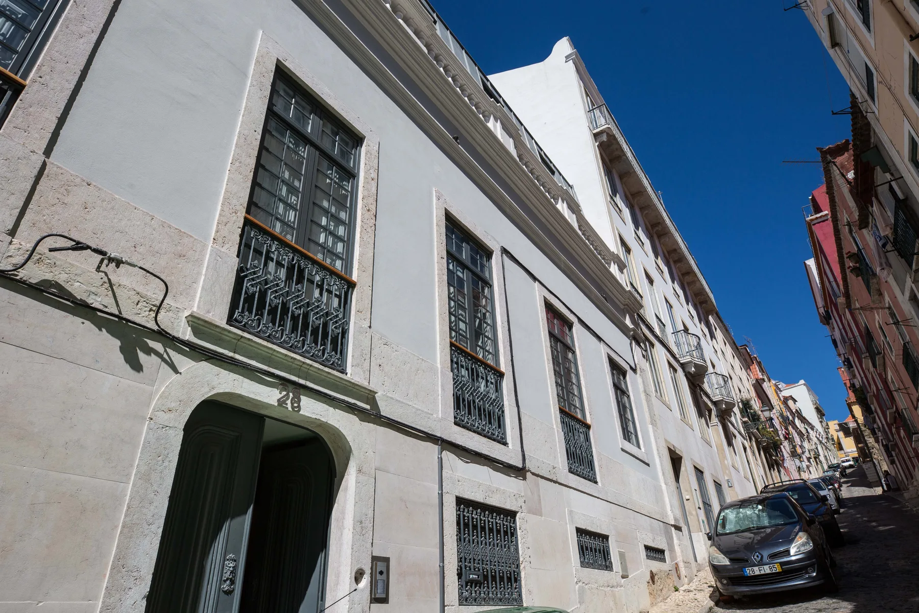 Una calle estrecha de la ciudad con edificios altos y coches aparcados.