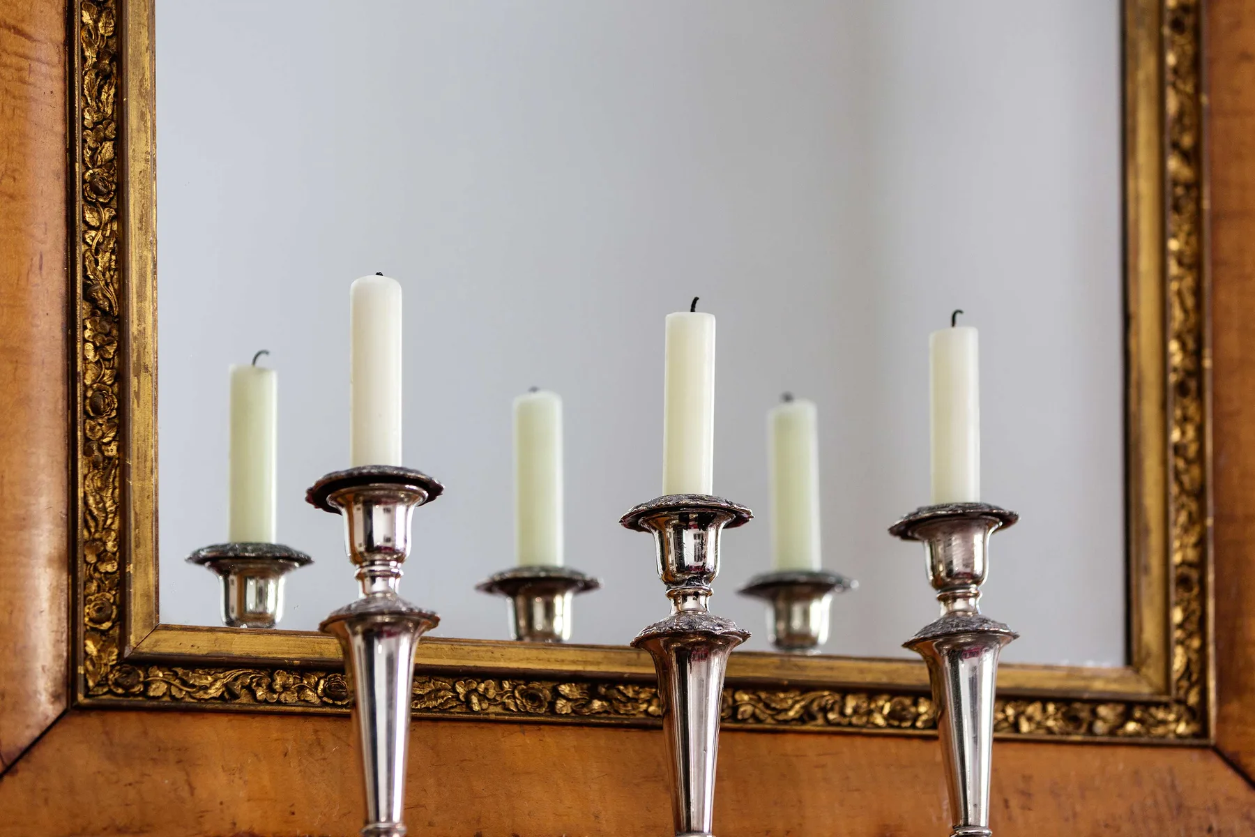 A decorative interior mirror reflects several candle holders and unlit candles.