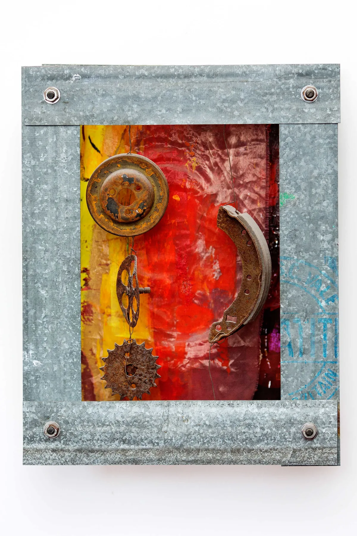 Abstract red and yellow artwork is displayed in a metal frame on a white wall.