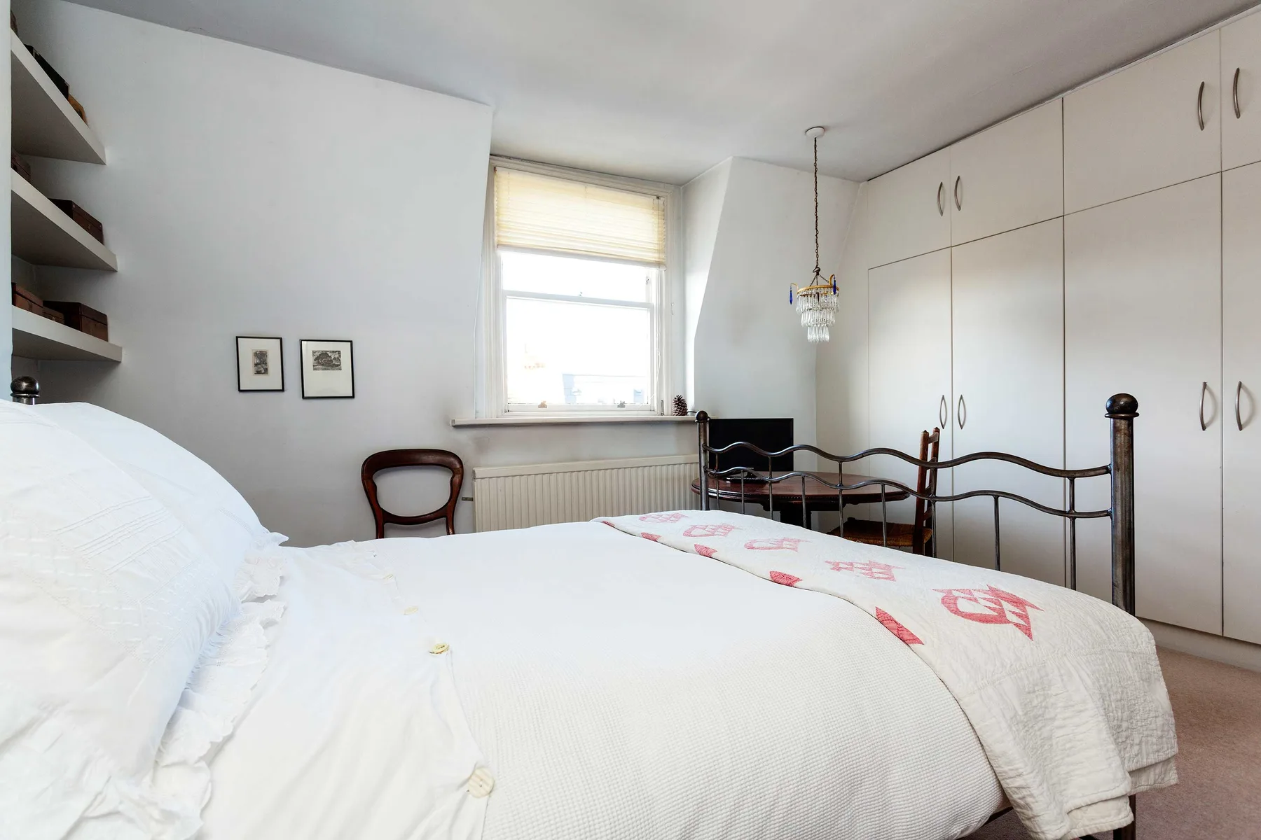Un dormitorio con una cama, armarios empotrados y una ventana.