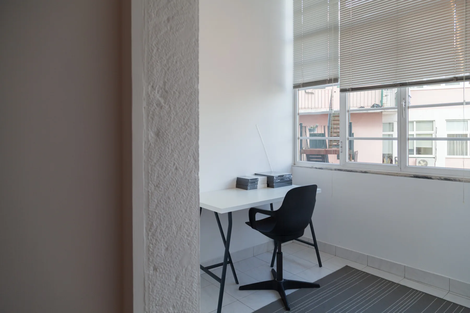Un espacio de trabajo luminoso con escritorio y silla junto a una ventana grande.