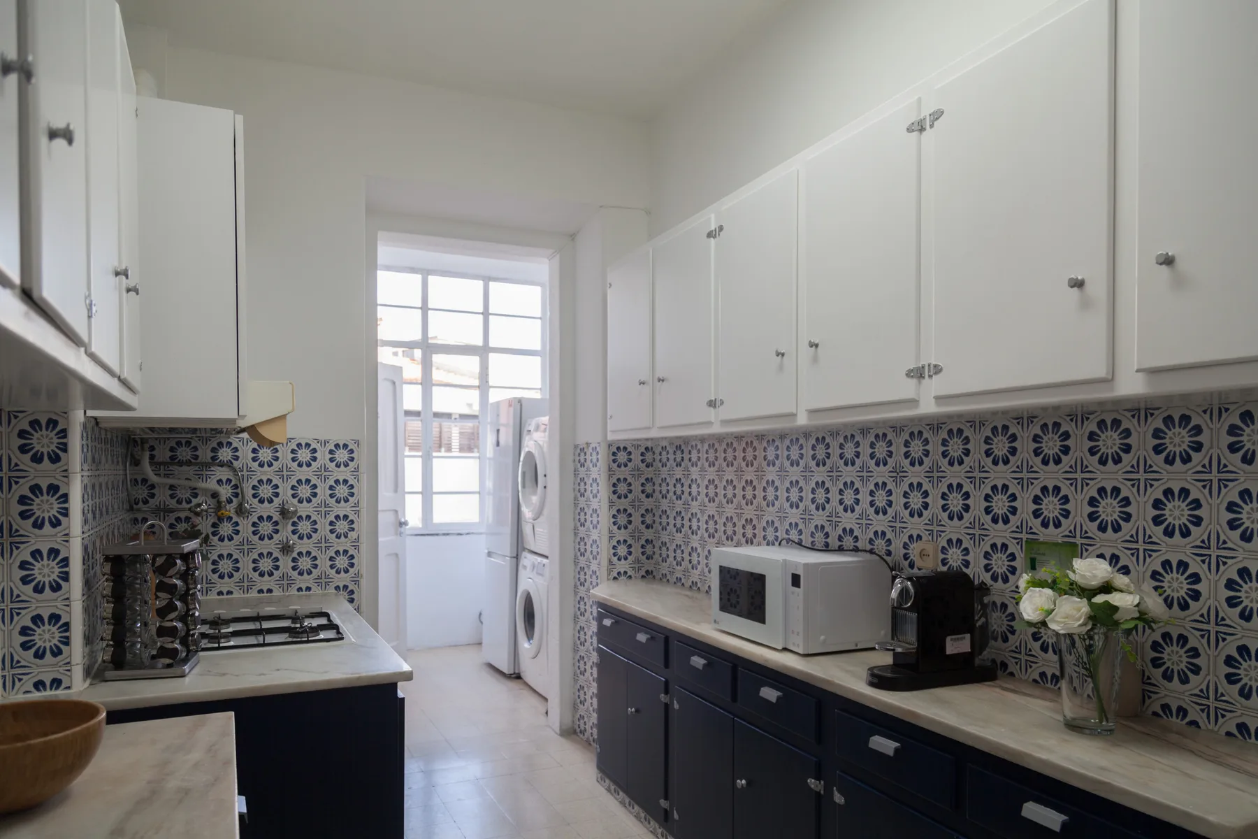 Una cocina luminosa con azulejos estampados y electrodomésticos sobre las encimeras.