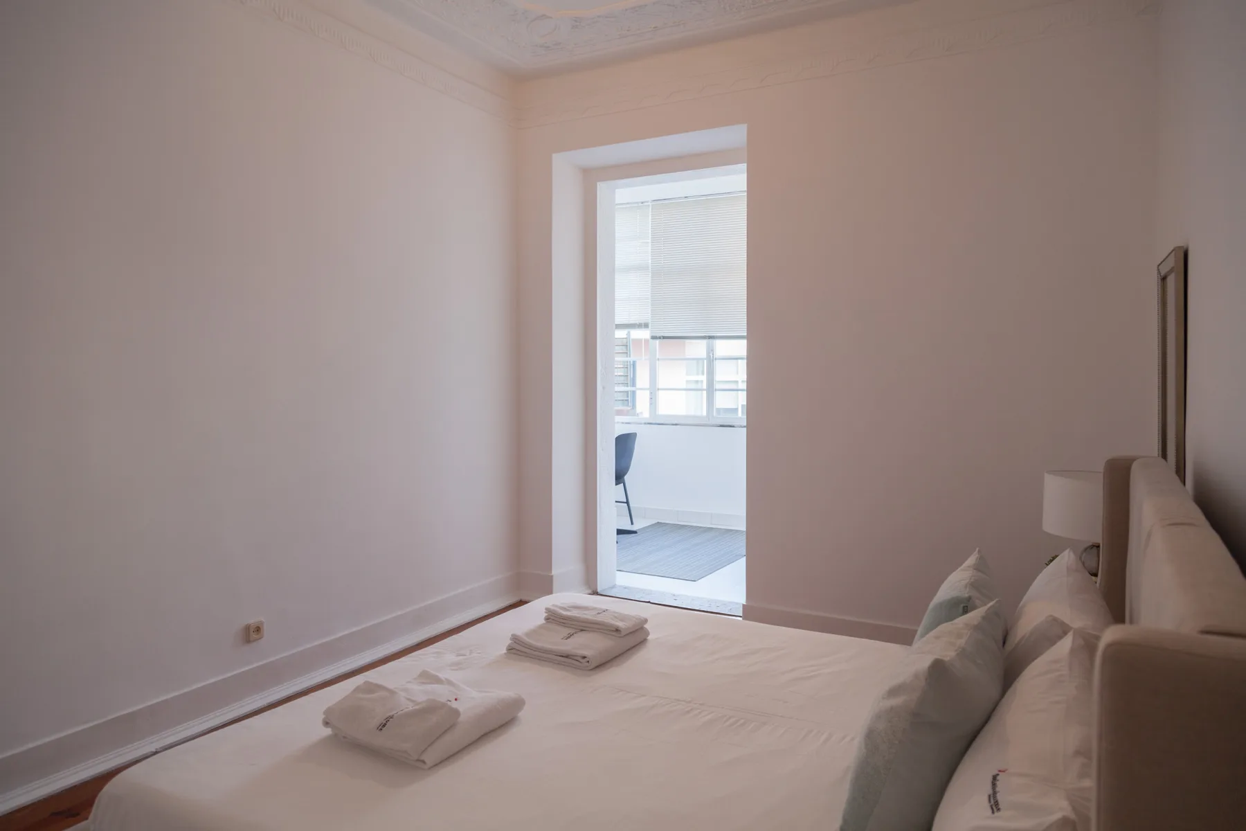 Dormitorio con una cama y una puerta abierta que da a una zona contigua luminosa.
