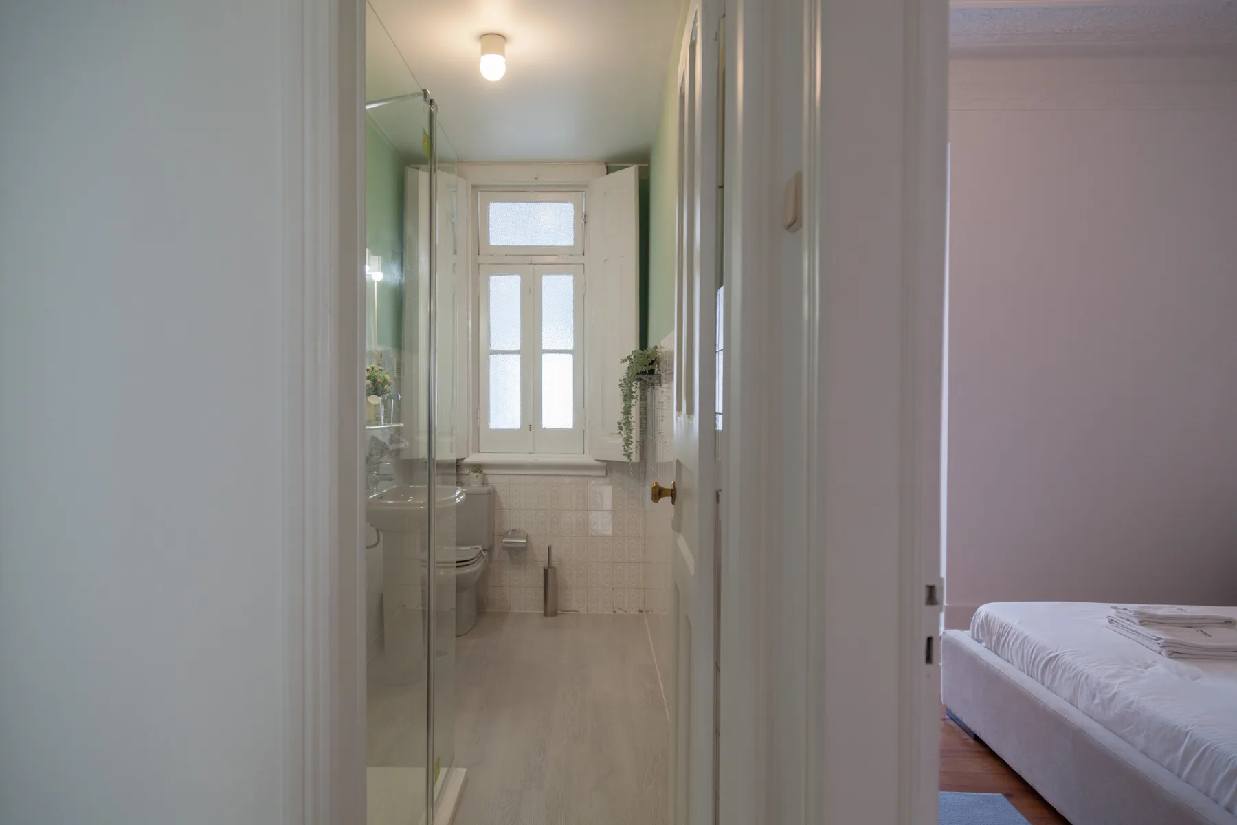 Se ve un dormitorio con una cama junto a un baño con ducha de vidrio.