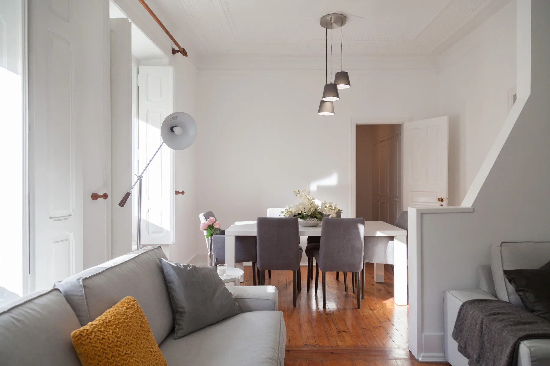 Una luminosa sala de estar y comedor con asientos, una mesa y lámparas colgantes.