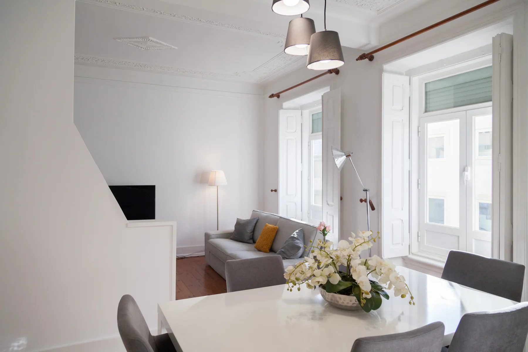 Un luminoso salón-comedor con asientos, una mesa y ventanas altas.
