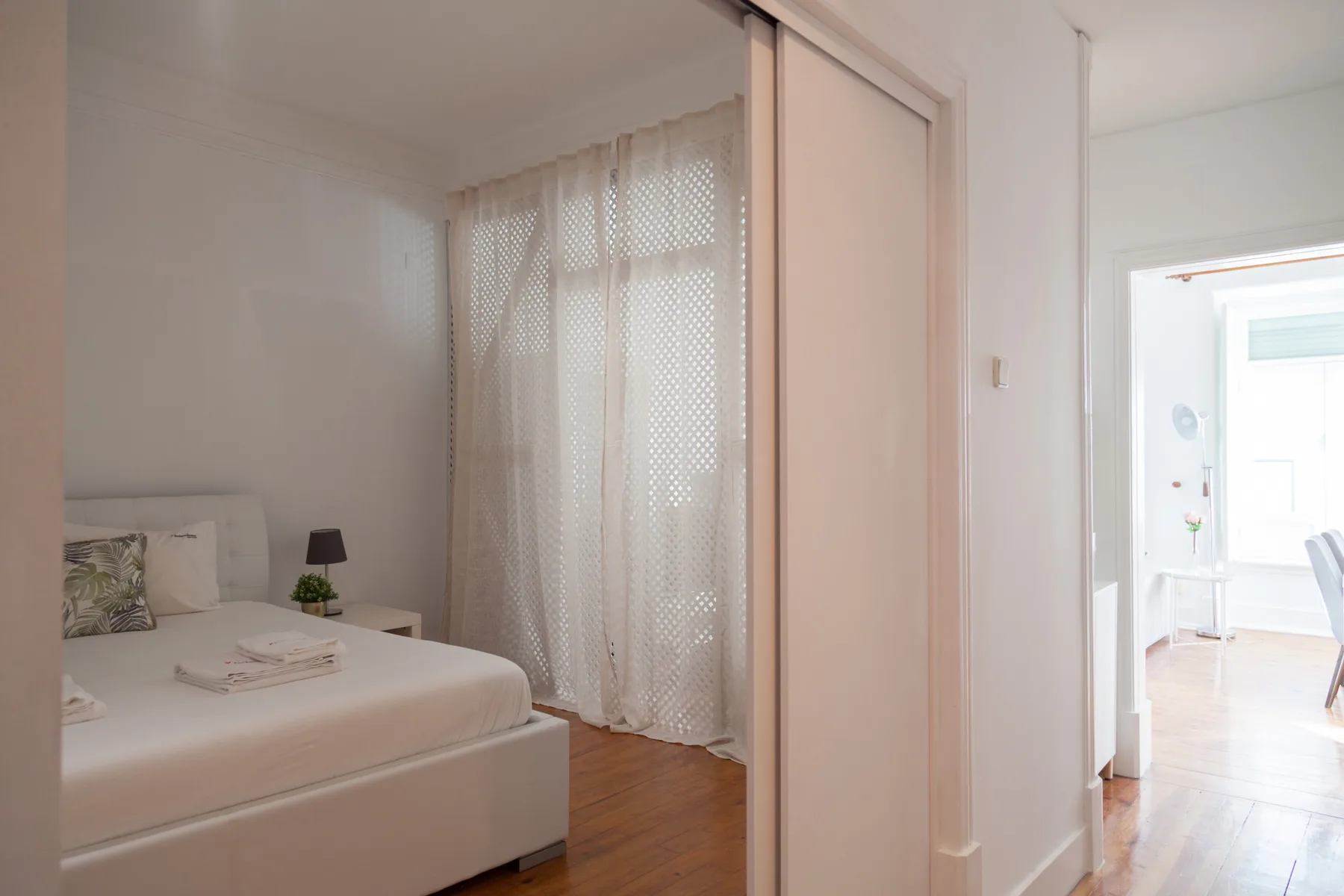 Dormitorio con una cama junto a cortinas translúcidas y una puerta corredera de armario.