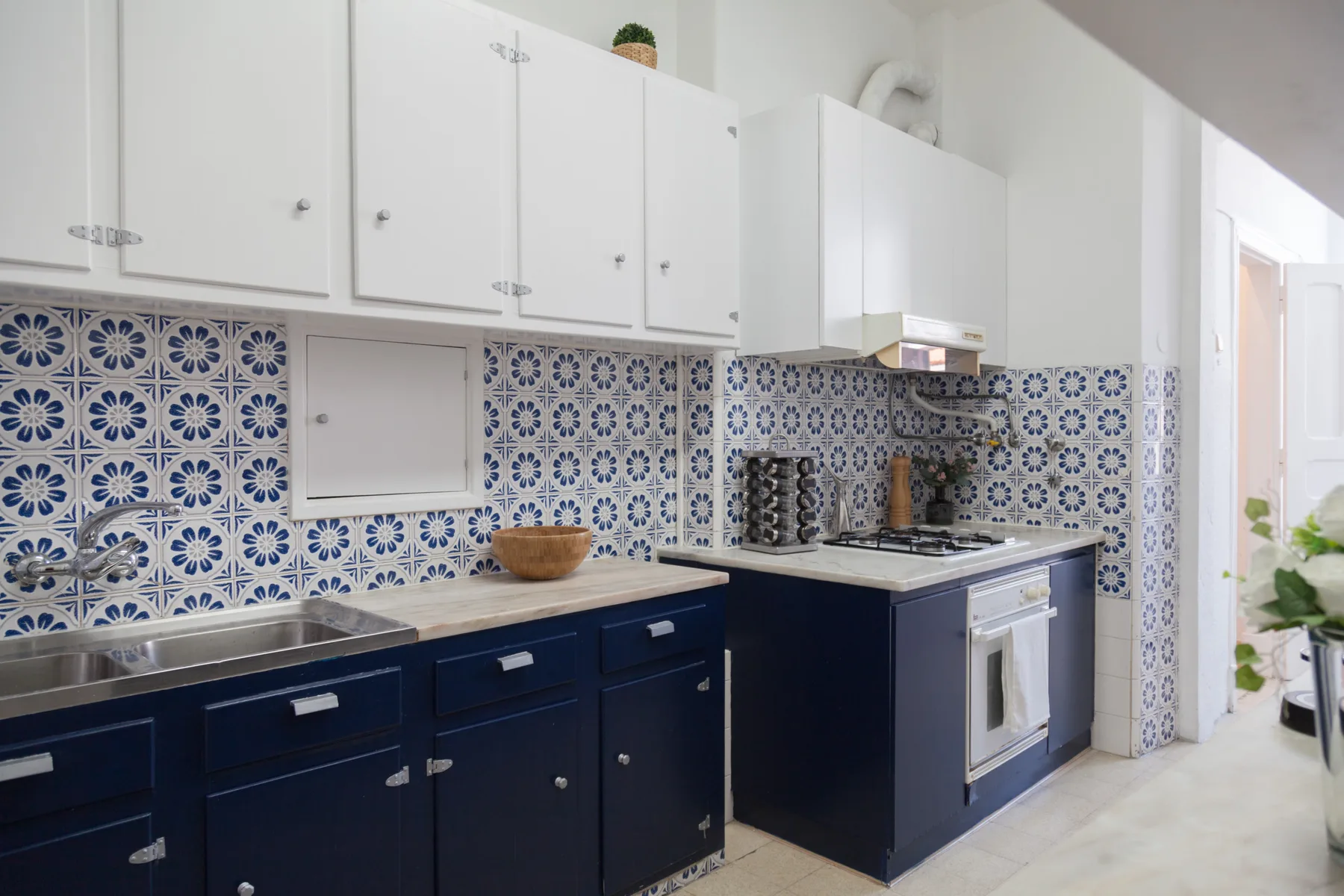 Una cocina luminosa con armarios azul oscuro y azulejos decorados.