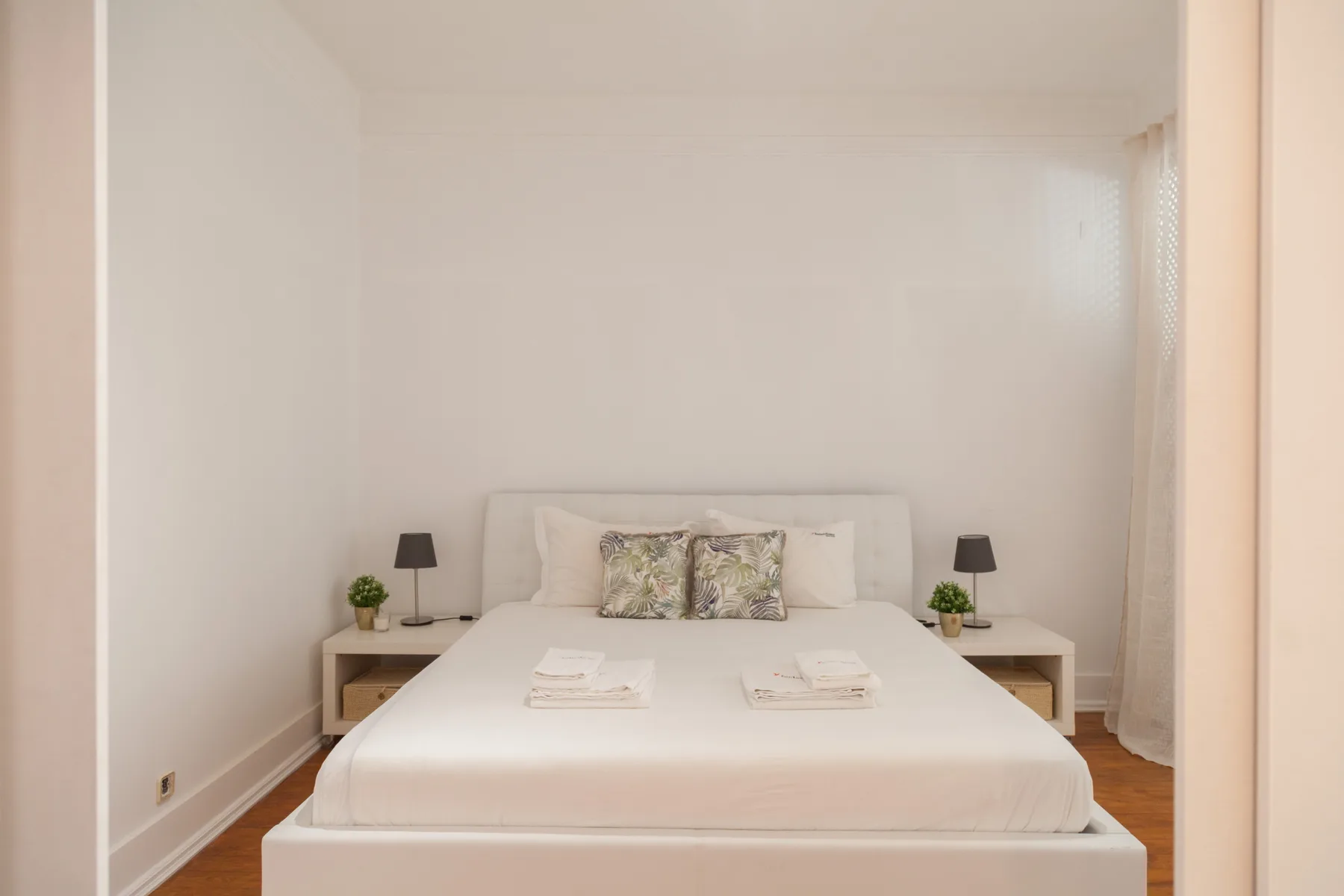 Un dormitorio con una cama bien hecha y mesillas a ambos lados.