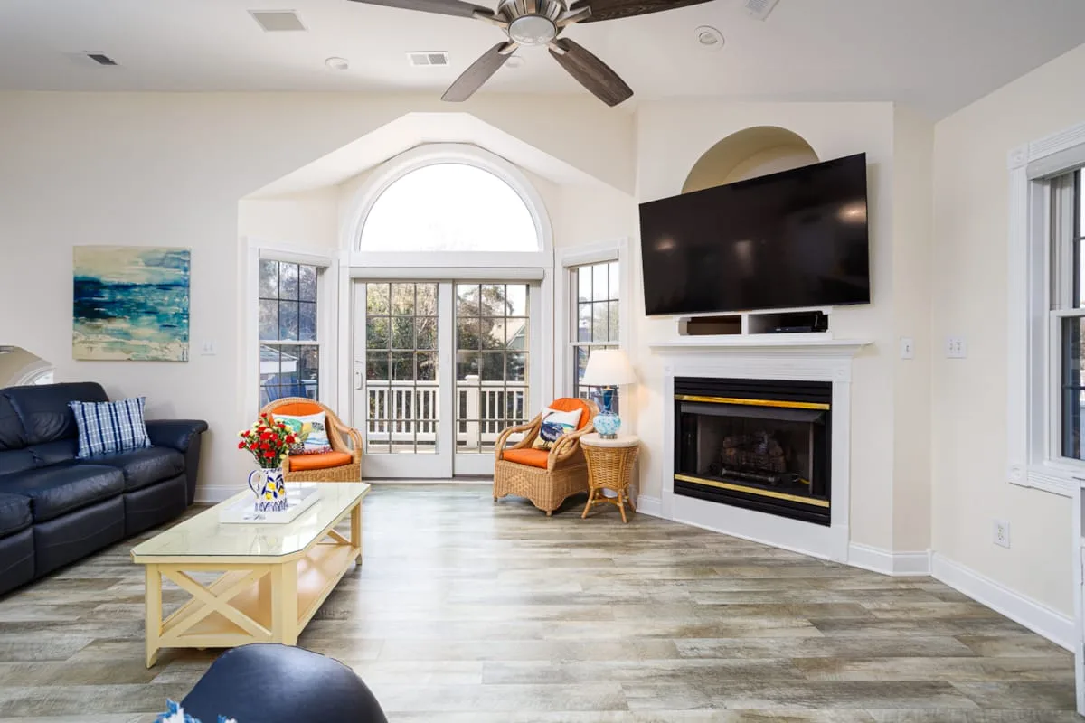 A bright living room with seating, a large television, and glass doors.