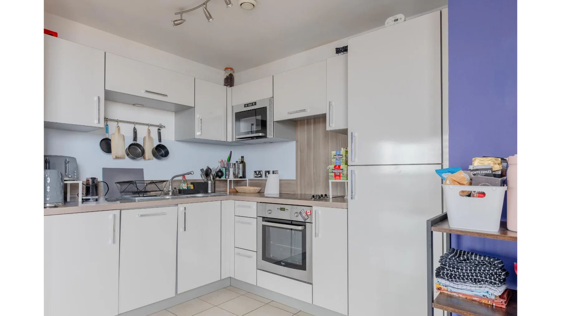 A bright kitchen with white cabinets and a built-in oven.