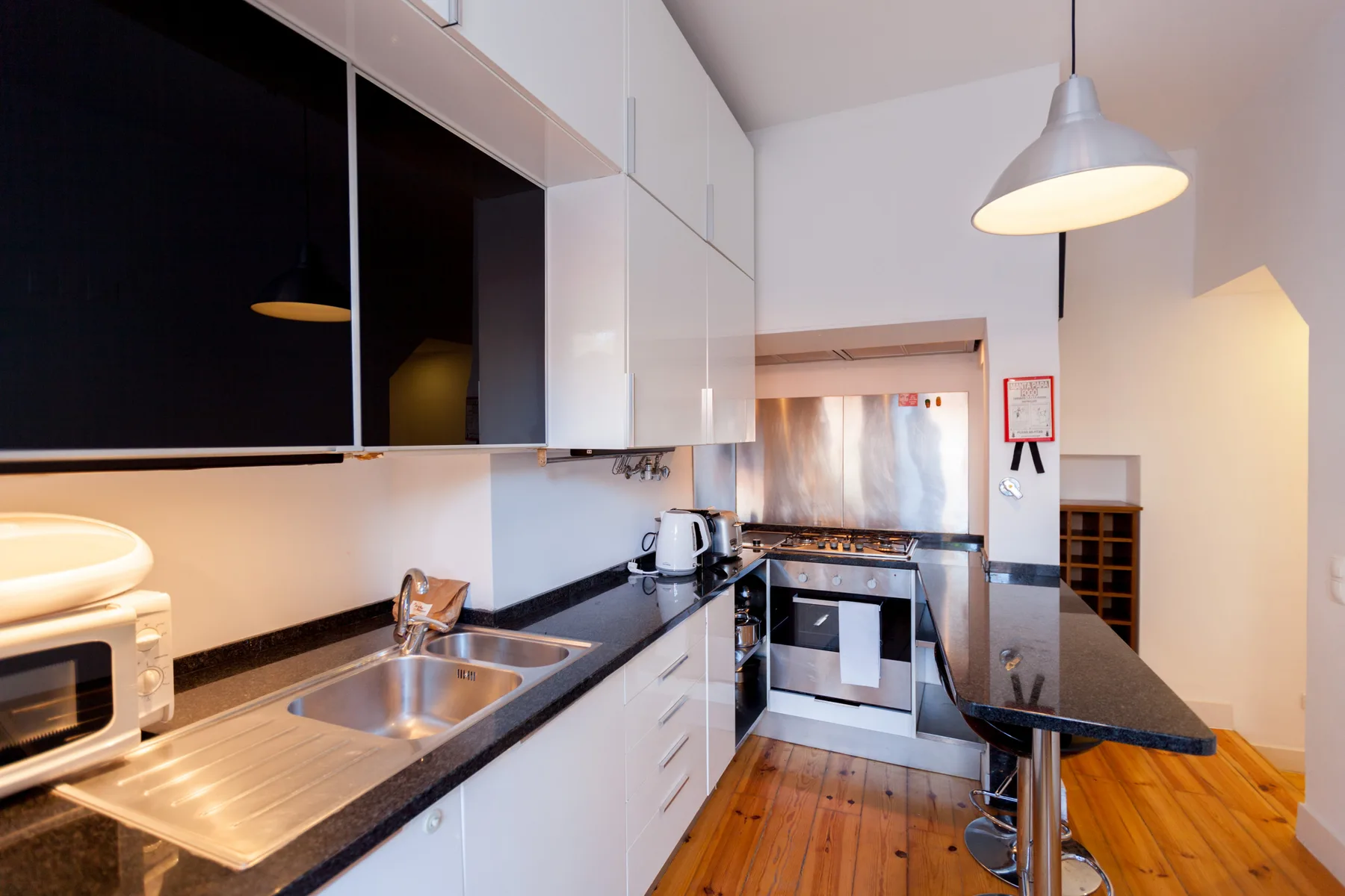 Una cocina compacta con armarios blancos, una encimera y una barra para comer.