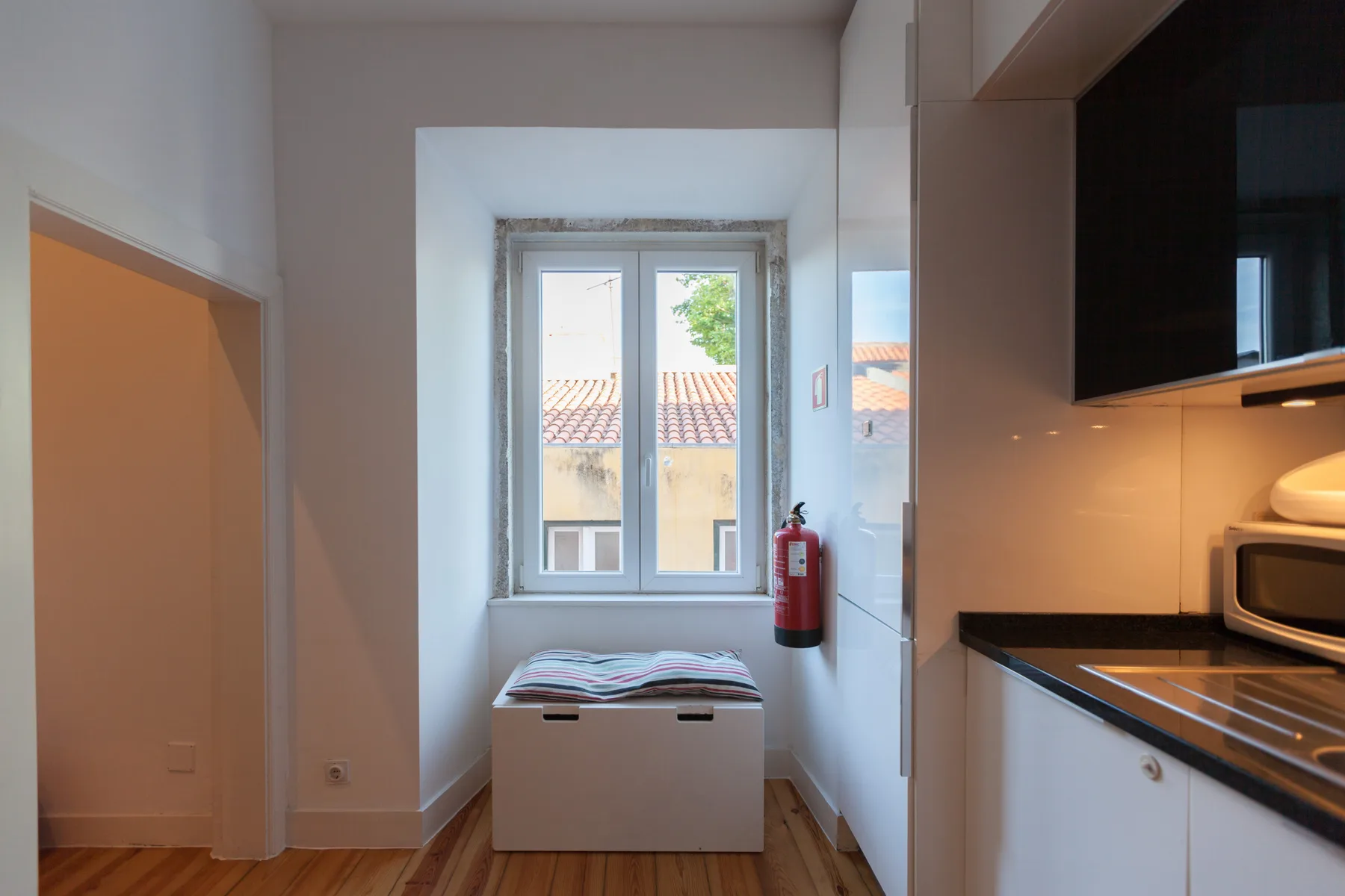 Una pequeña zona de cocina con una ventana y un banco debajo.