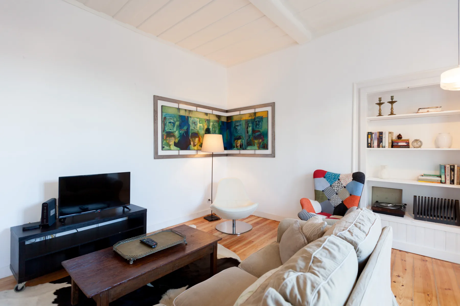 Una sala luminosa con televisor, asientos y estantes empotrados.