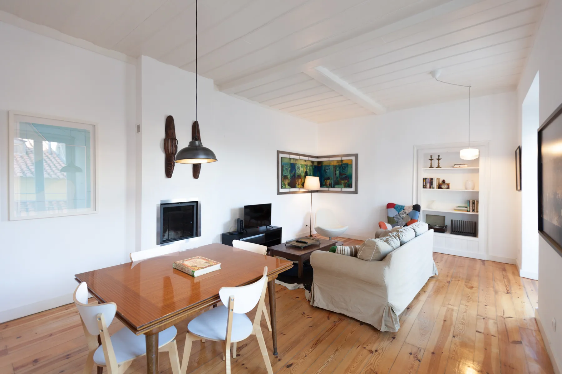 Sala de estar y comedor con asientos, un televisor y una mesa de madera.