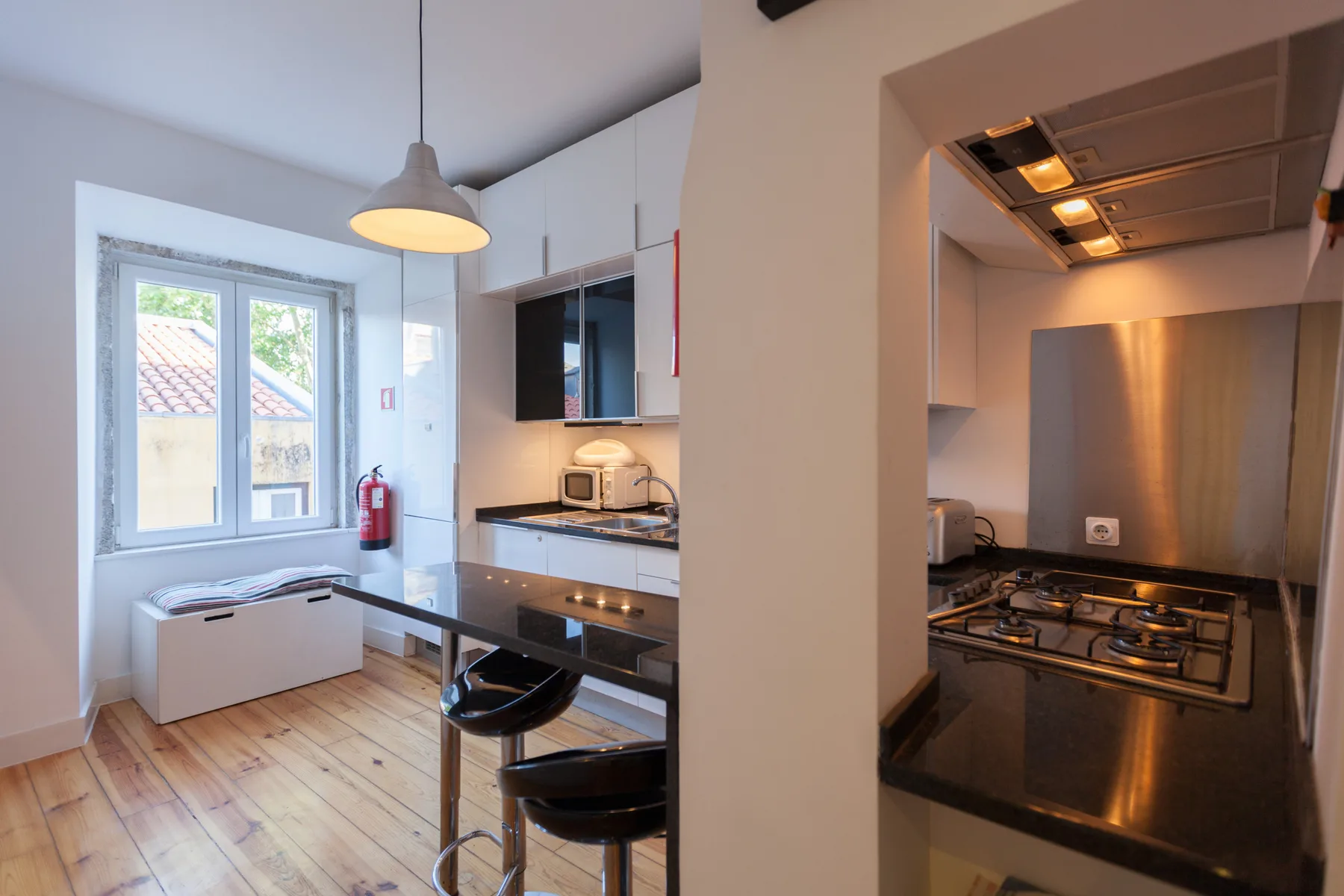 Cocina luminosa con una barra para comer y asientos negros junto a la ventana.