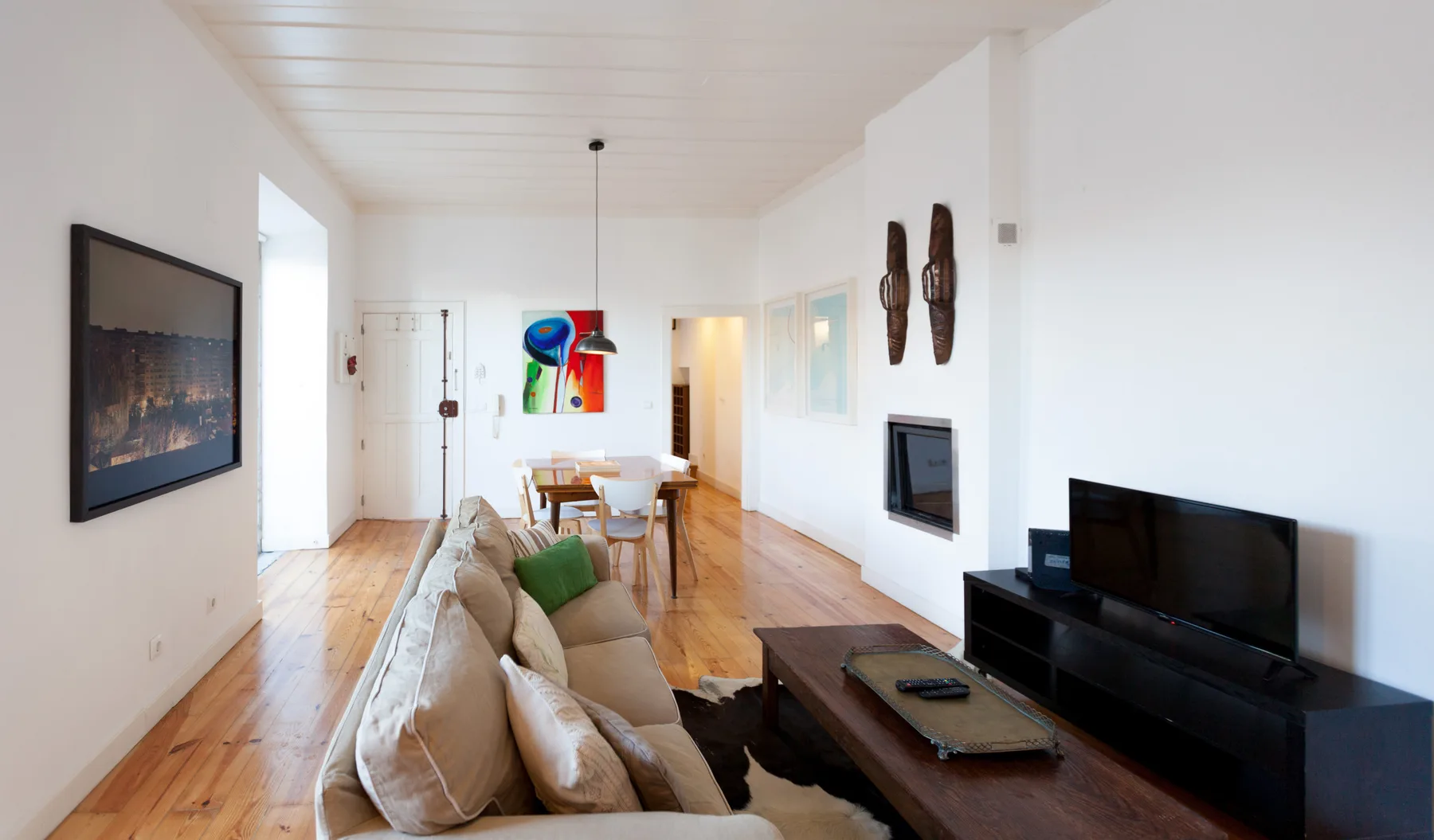 Una luminosa sala de estar y comedor con asientos, un televisor y una mesa de madera.