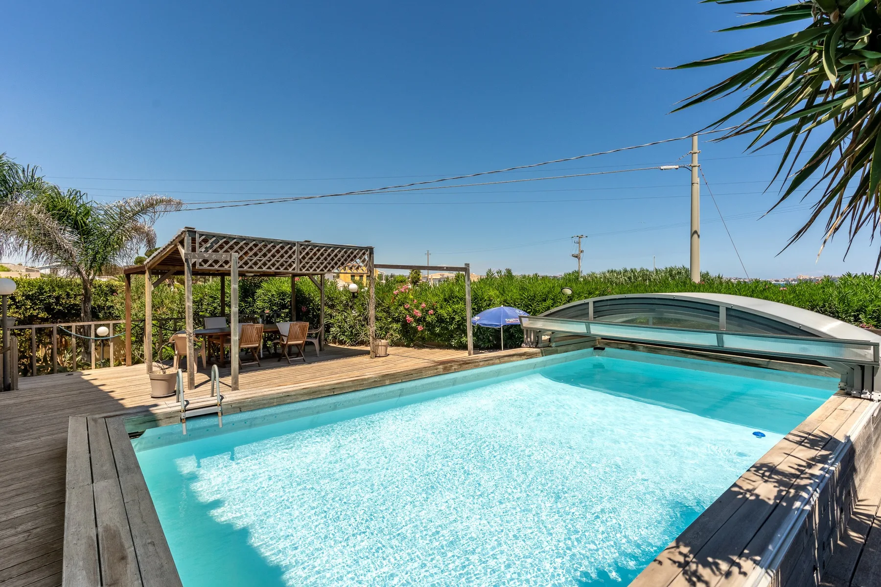 An outdoor swimming pool beside a wooden deck and garden seating.