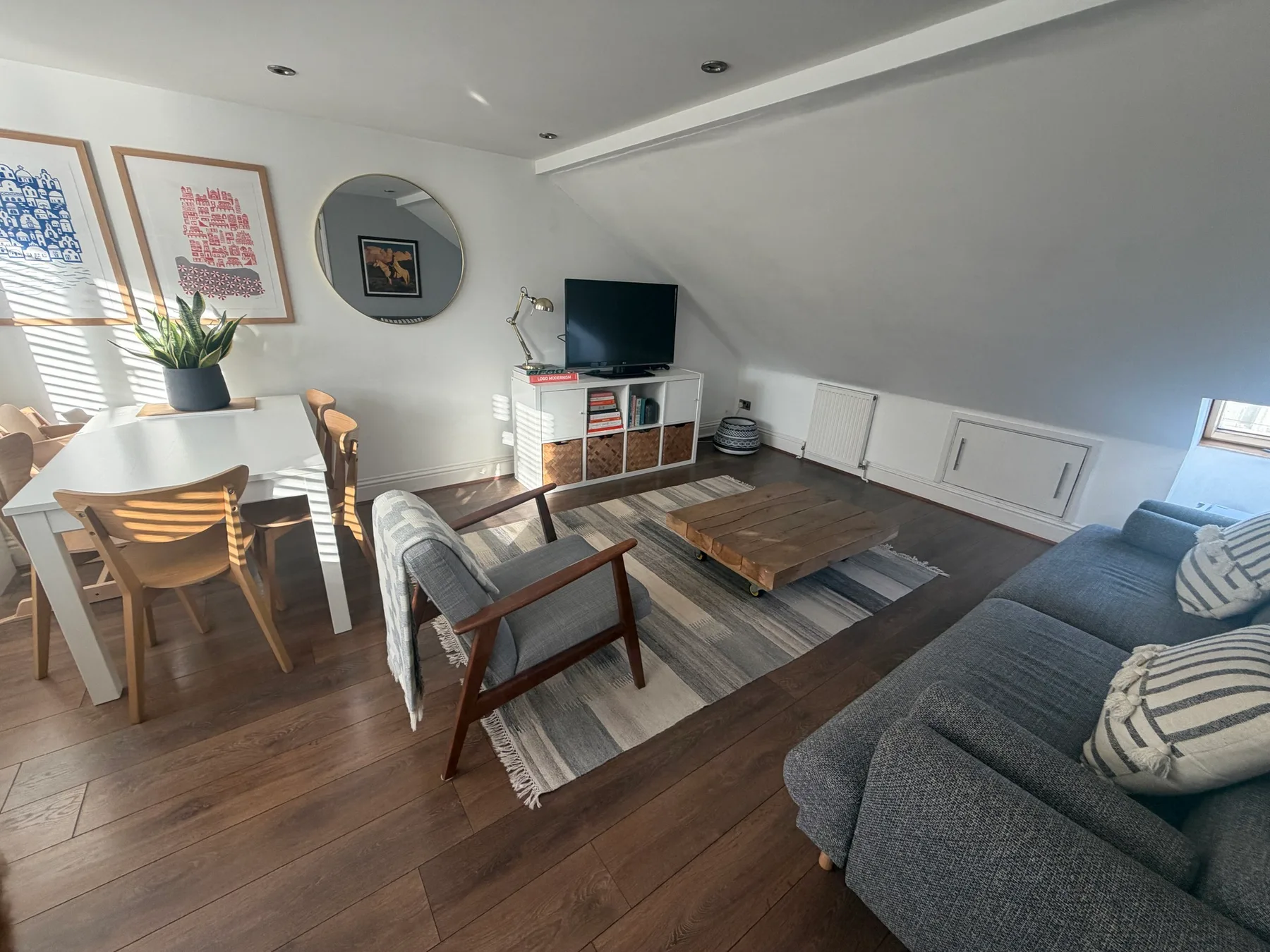 A living room with a dining table, seating, and a television.