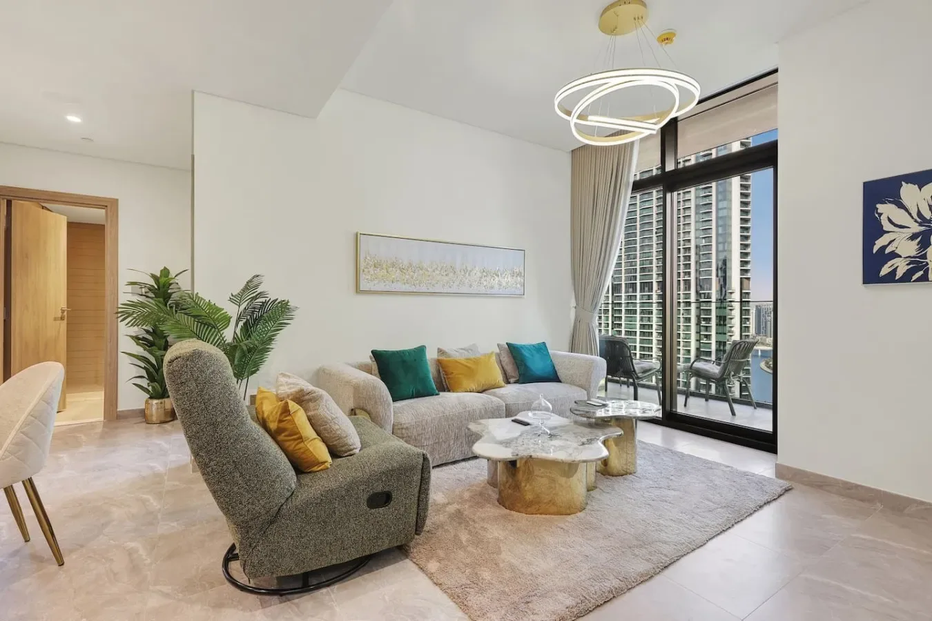 Una sala luminosa con asientos alrededor de una mesa de centro junto a grandes ventanas.