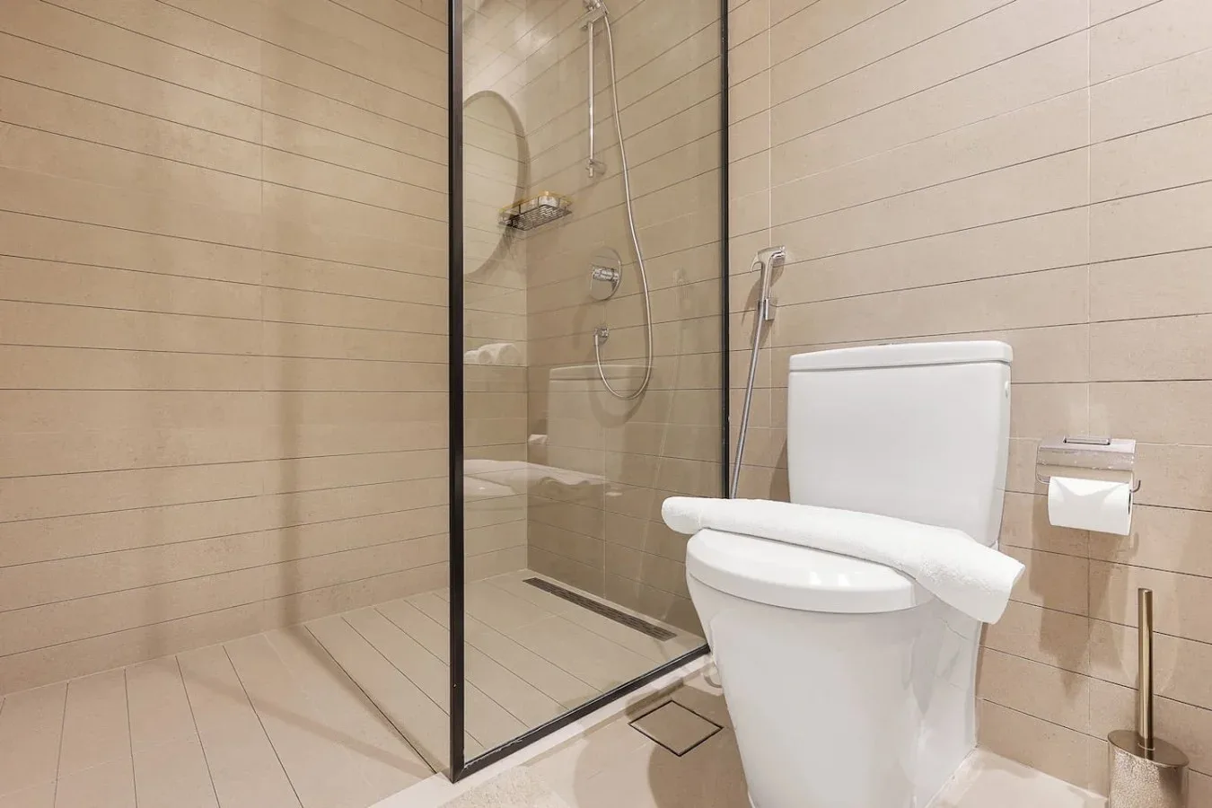 Un baño alicatado con ducha de vidrio e inodoro.