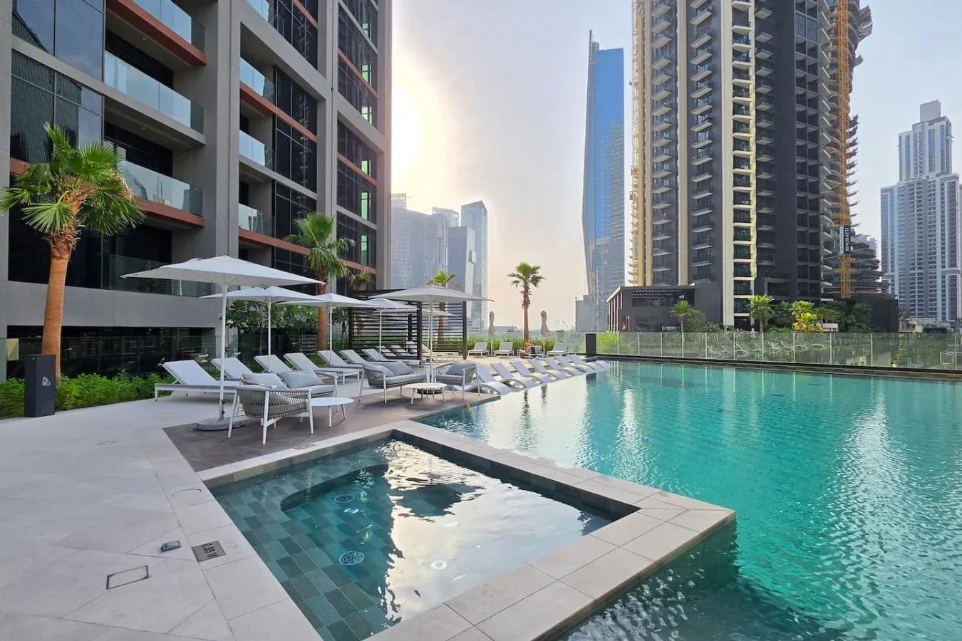 Una piscina en una azotea junto a edificios modernos, con asientos junto a la terraza.