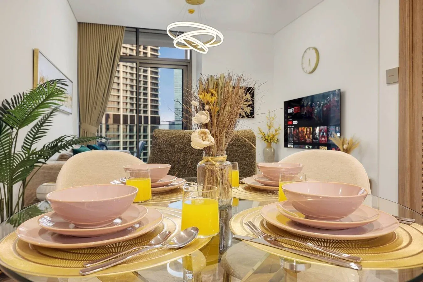 Comedor con una mesa de cristal puesta con platos rosas y bebidas amarillas.