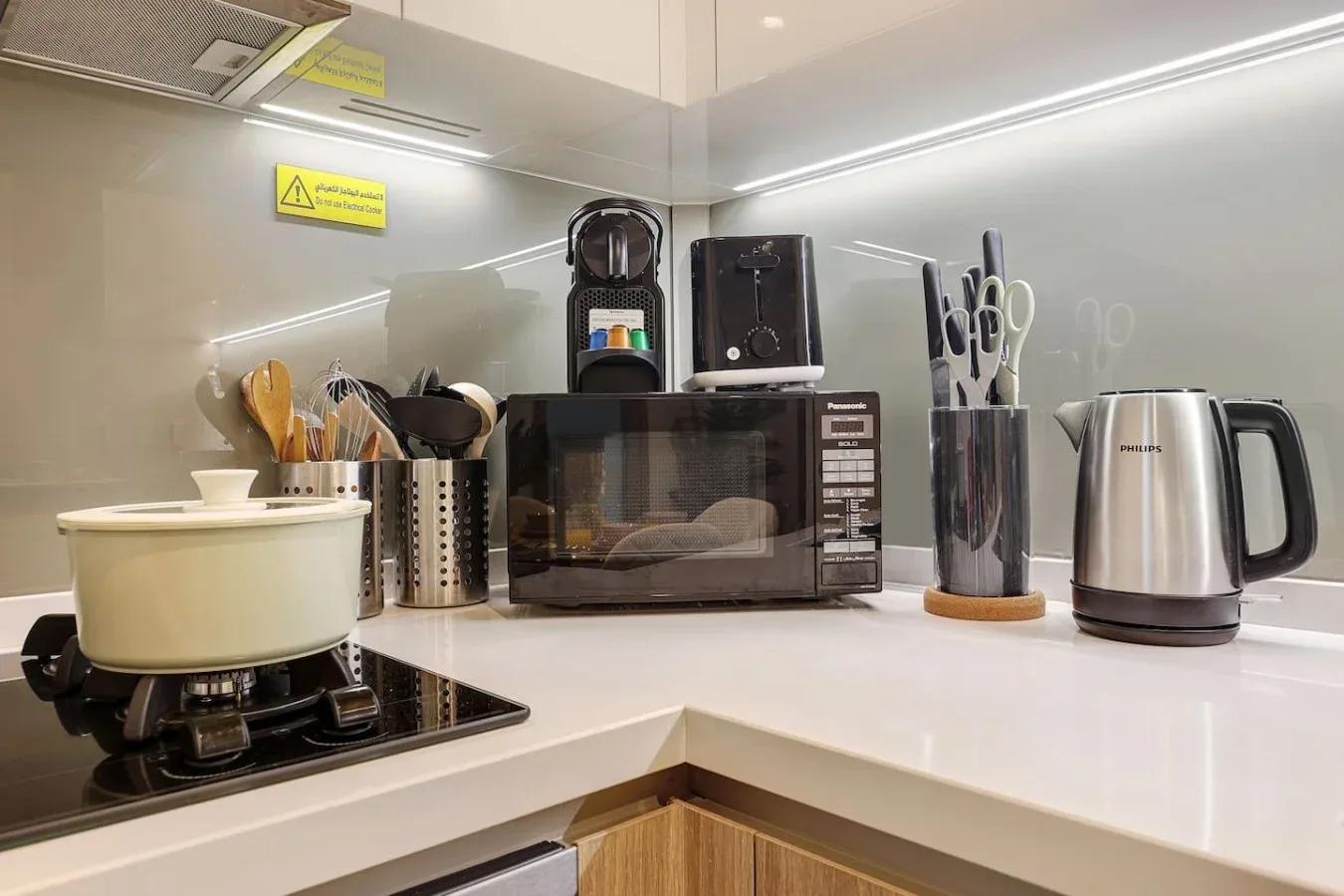 Una encimera de cocina luminosa con microondas, hervidor y utensilios de cocina.