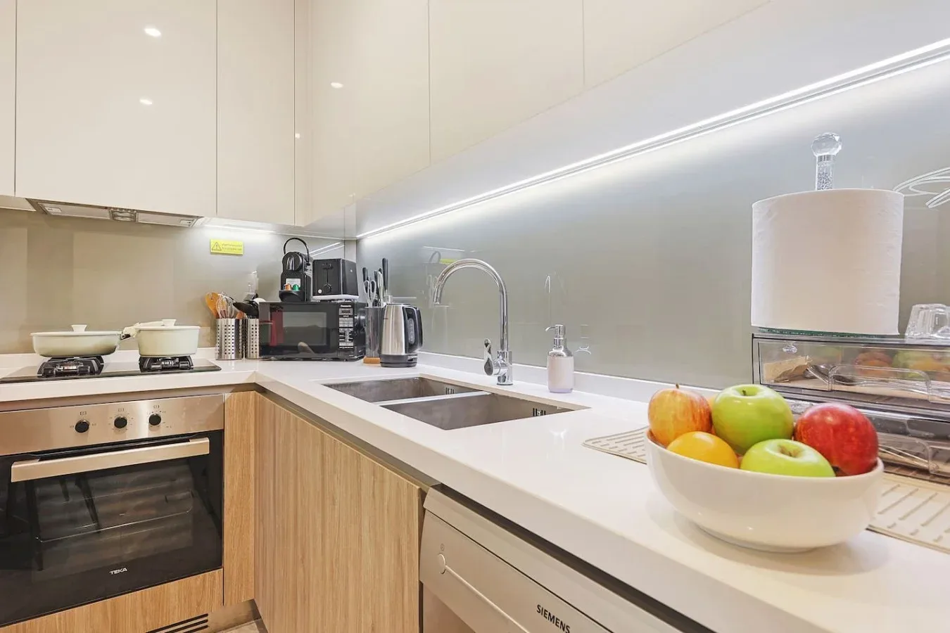 Una cocina moderna con fregadero, encimera y un cuenco de fruta.