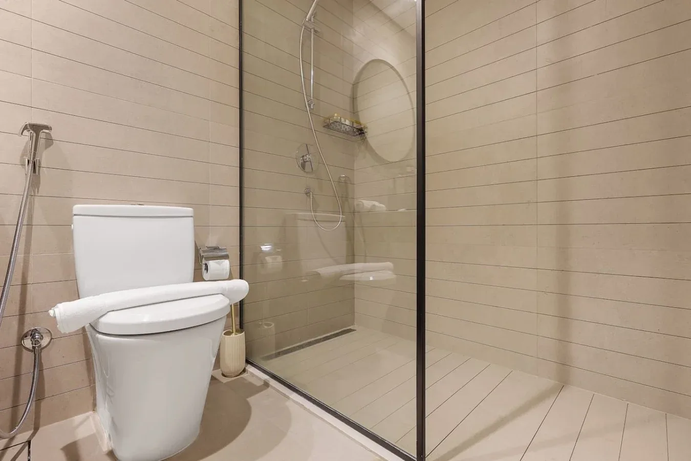 Un baño con un inodoro junto a una ducha con mampara de vidrio.