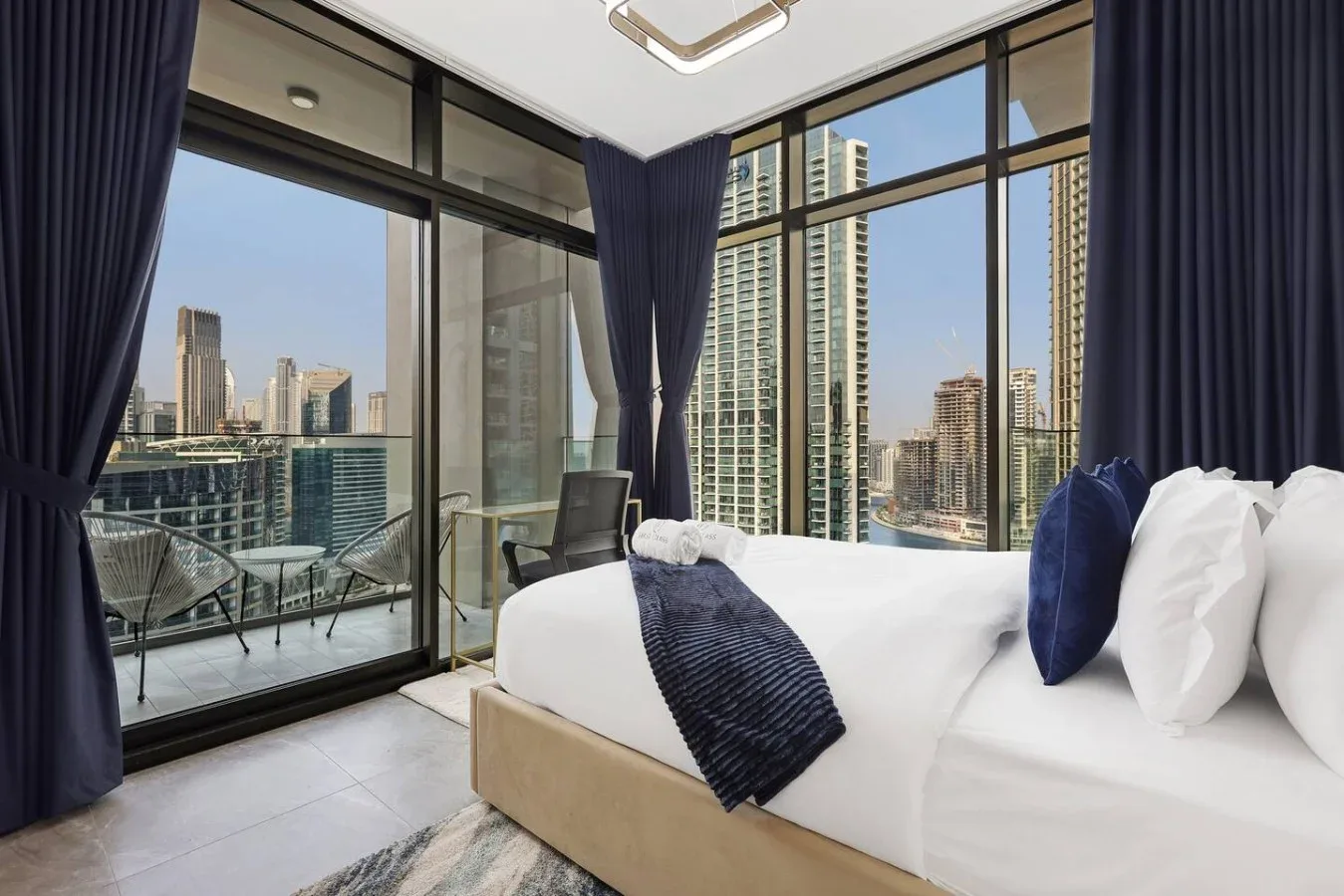 Un dormitorio con ventanales de suelo a techo y vistas al horizonte urbano.