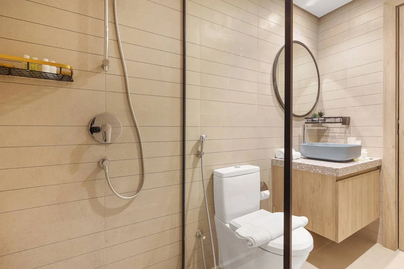 Un baño con ducha de vidrio, inodoro y lavabo sobre un mueble.