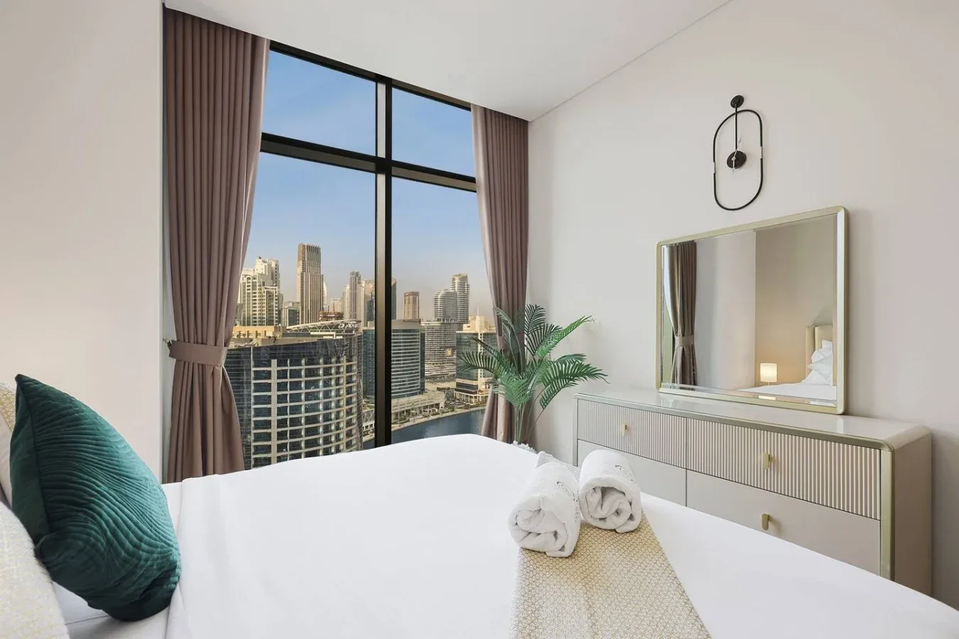Un dormitorio luminoso con una gran ventana que da a edificios de la ciudad.