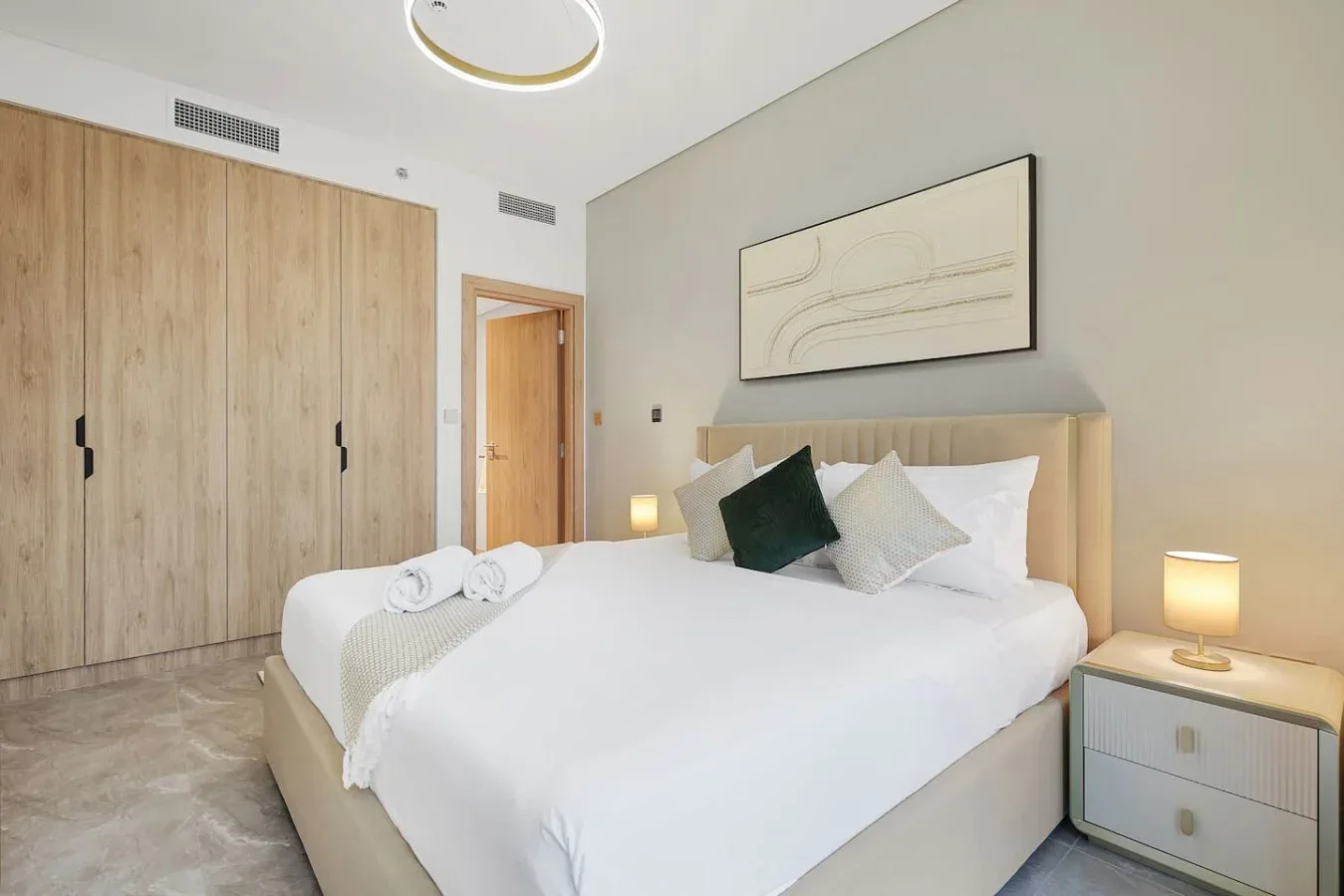 Un dormitorio luminoso con una cama bien hecha y armarios de madera clara.