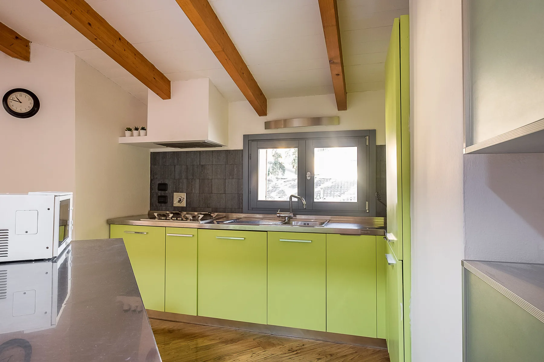 Una cocina luminosa con gabinetes verdes, una estufa y una ventana.