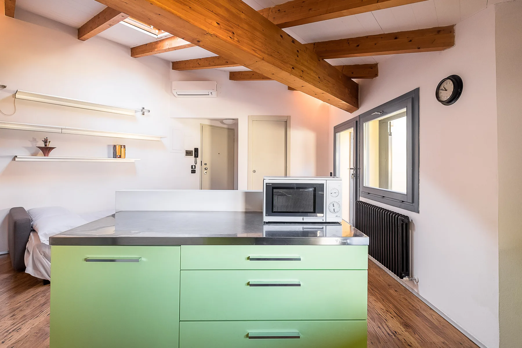 Una cocina compacta con gabinetes verdes y vigas de madera expuestas en el techo.