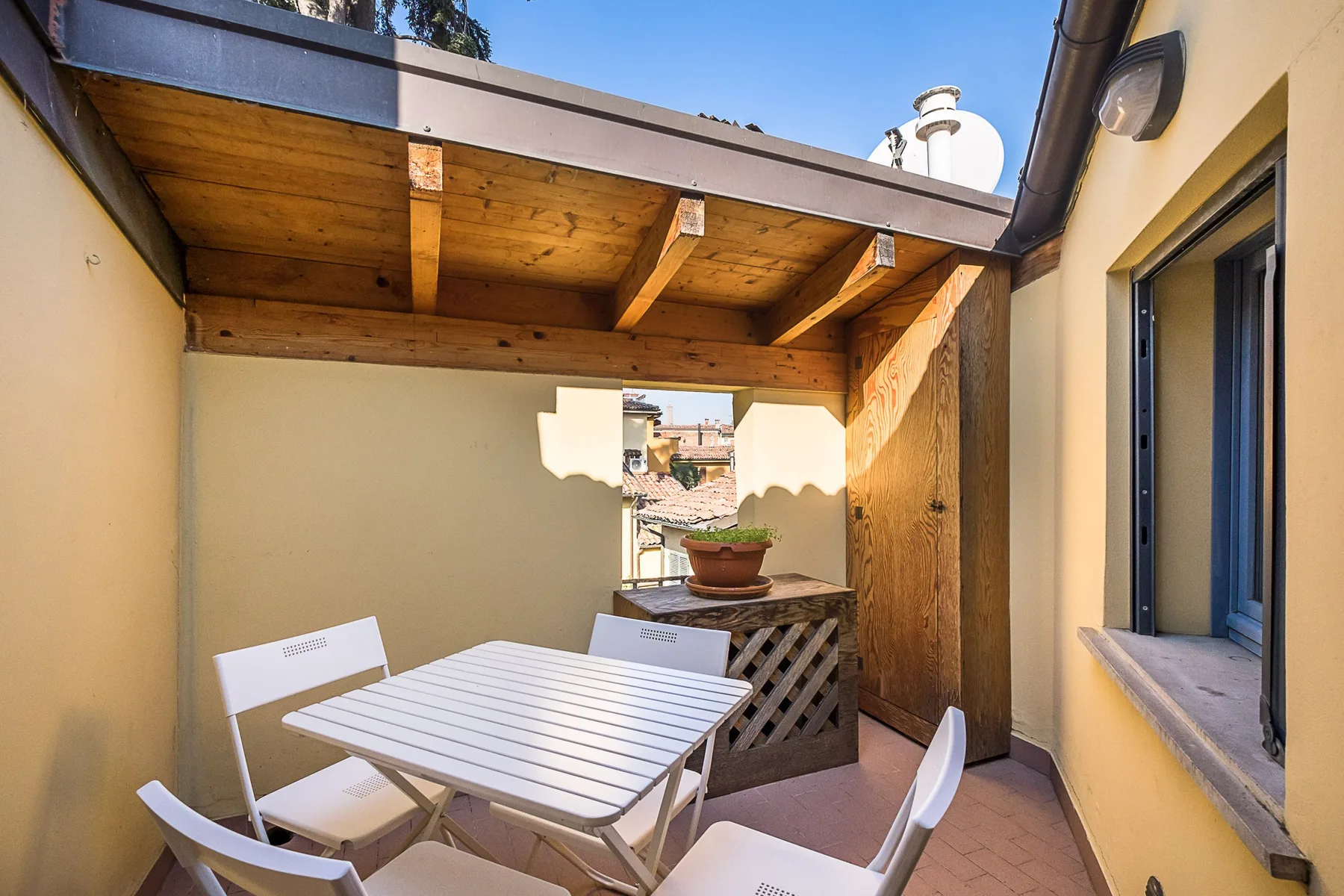 Un patio exterior cubierto con una mesa blanca y asientos.