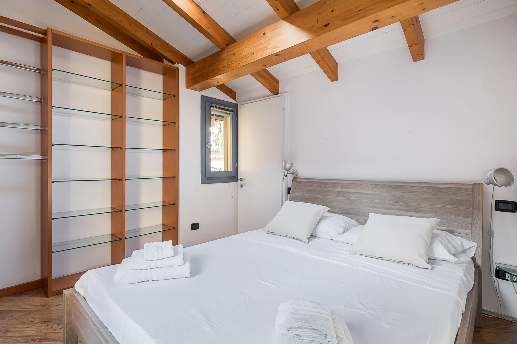 Un dormitorio con una cama grande bajo vigas de madera expuestas en el techo.