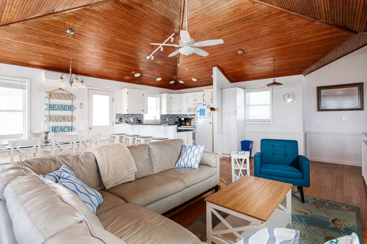 A bright living room with a sectional seating area, coffee table, and open kitchen.