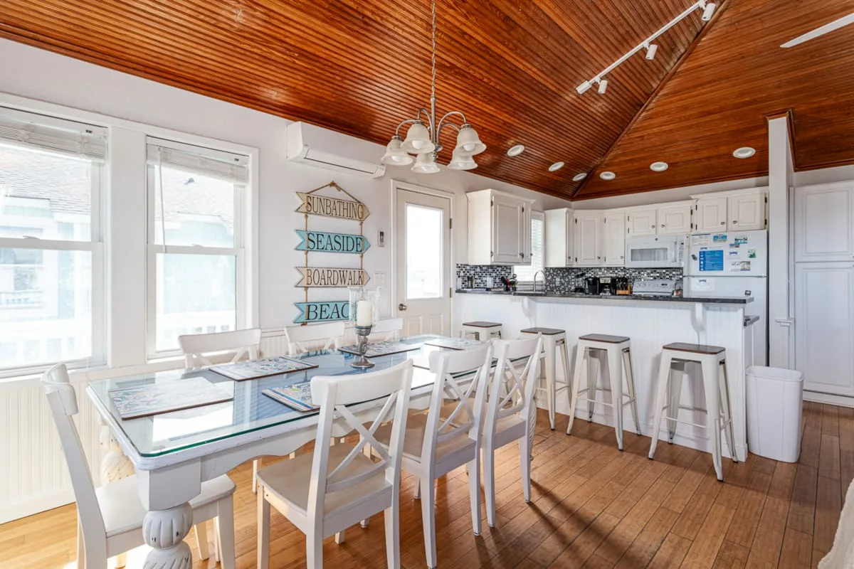 A bright kitchen and dining area with a long table and breakfast bar.