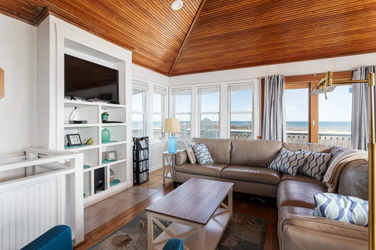 A bright living room with sectional seating, a coffee table, and windows overlooking the water.