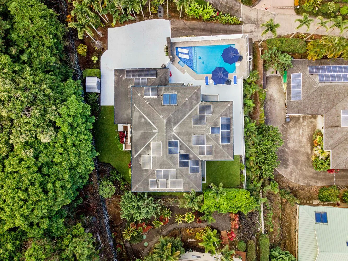 Vista aérea de una casa con paneles solares en el techo y una piscina.