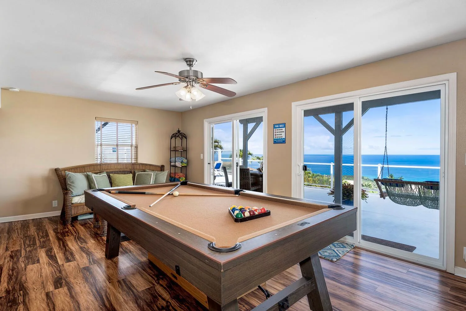 Una habitación con mesa de billar, asientos y grandes ventanas con vistas al océano.