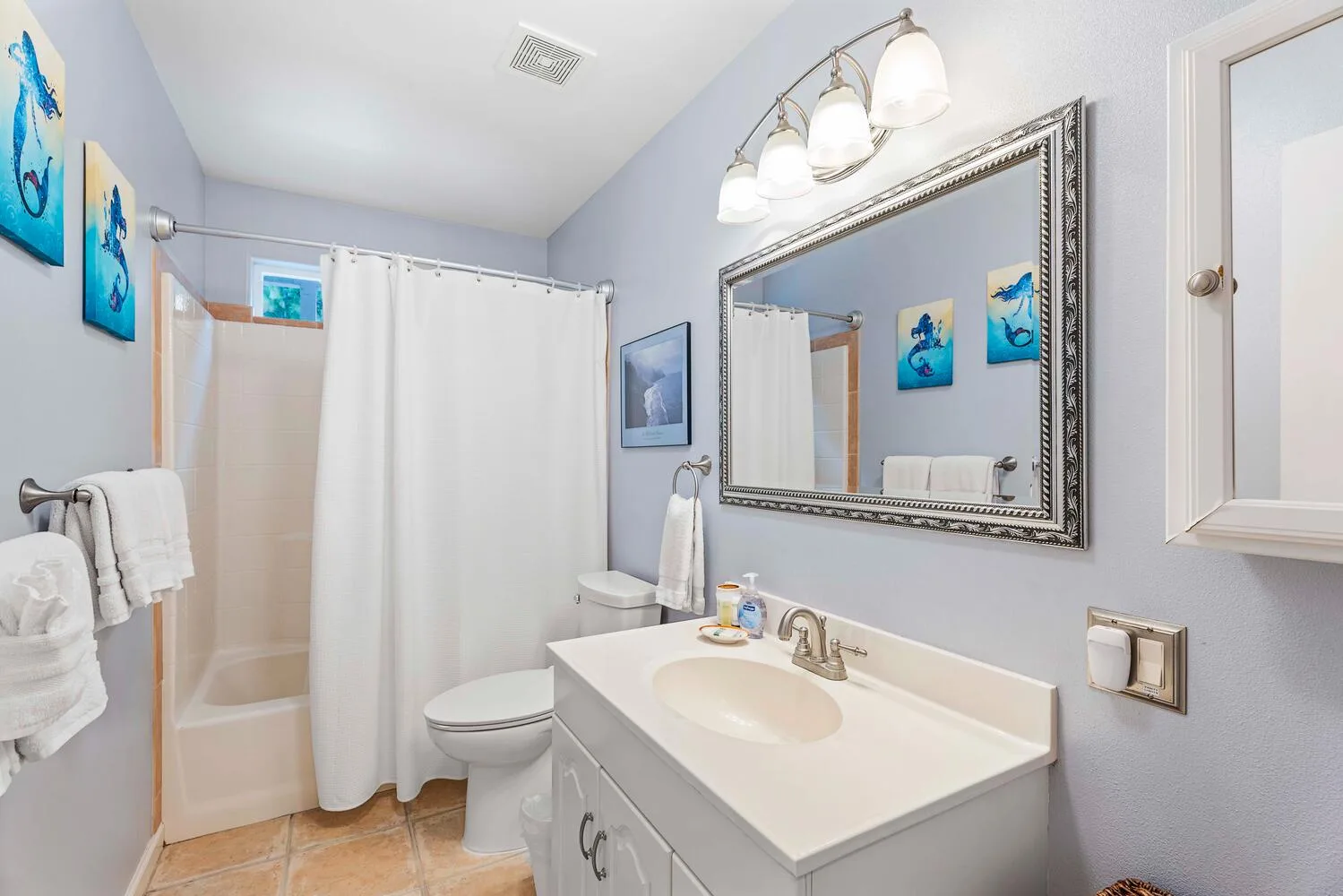 Baño con lavabo, espejo, inodoro y bañera con cortina.