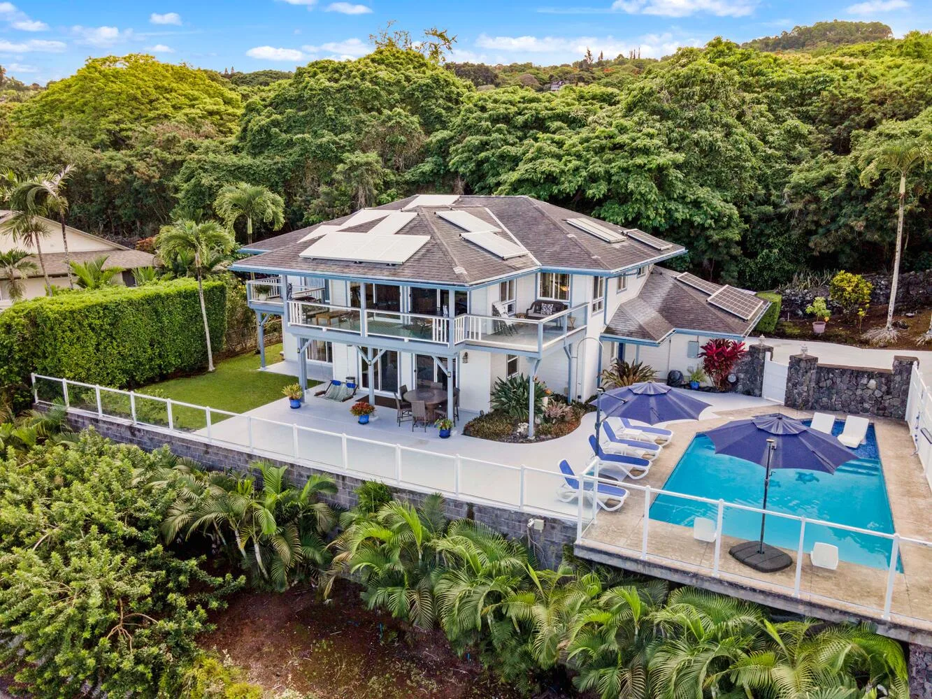 Una casa moderna da a una piscina, rodeada de árboles frondosos.