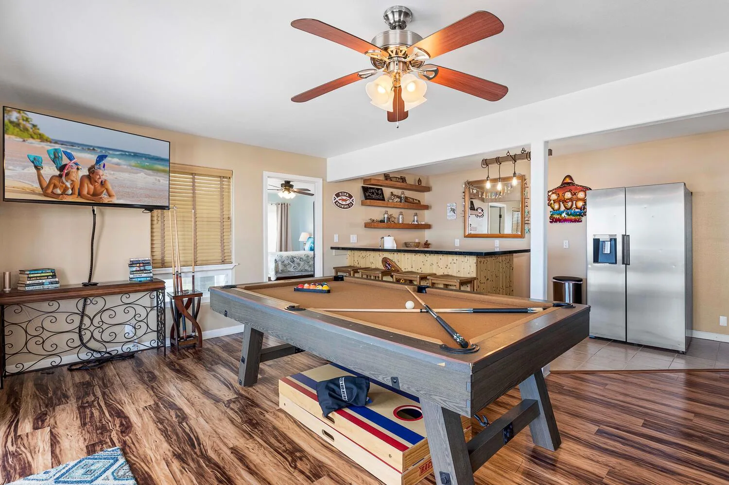 Sala de juegos con mesa de billar, televisor de pared y refrigerador.
