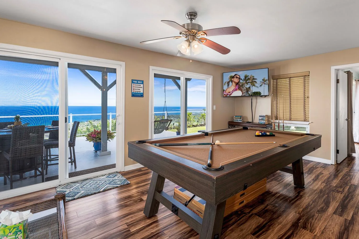 Sala de juegos con una mesa de billar, ventanas y vistas al océano.