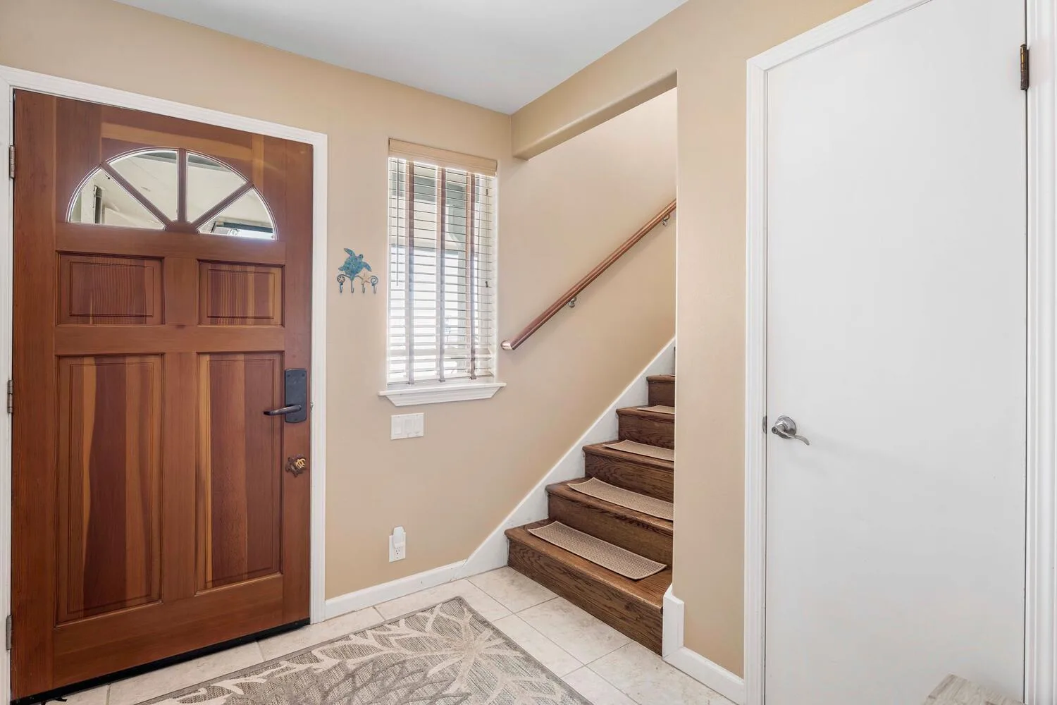 Una entrada con una puerta de madera y escaleras junto a una ventana.